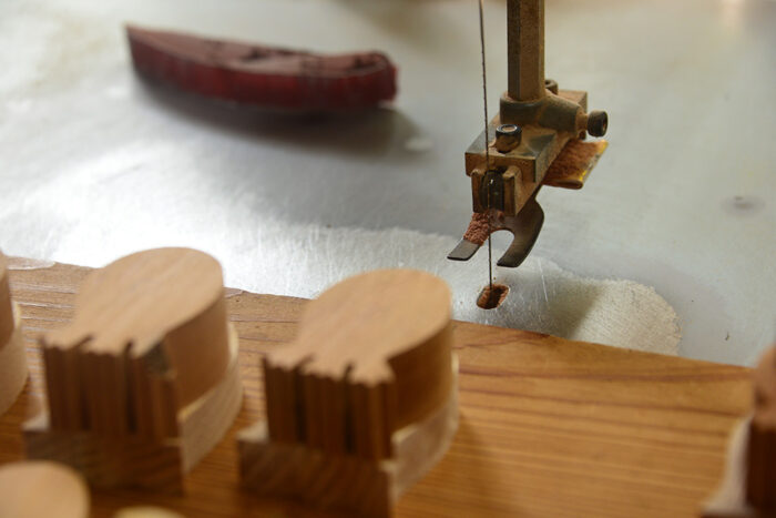 アマビエの体の輪郭を切り出す機械と、切り出されたラフな状態のアマビエクラフト